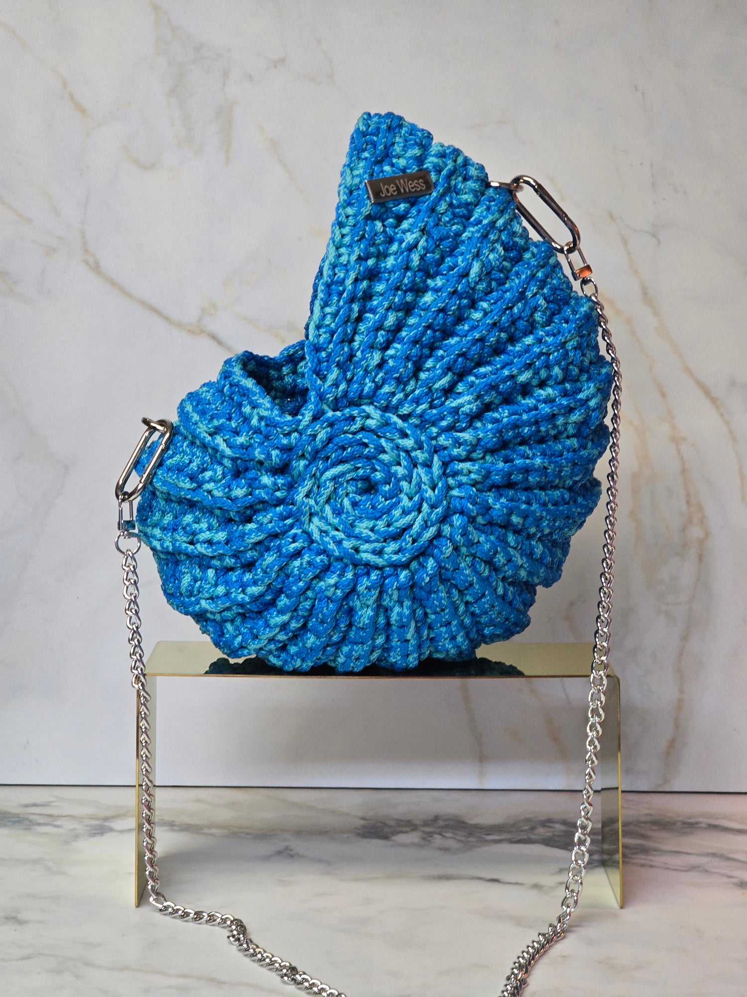 Handcrafted blue crochet purse featuring intricate stitching, a structured silhouette, and a timeless, elegant design.