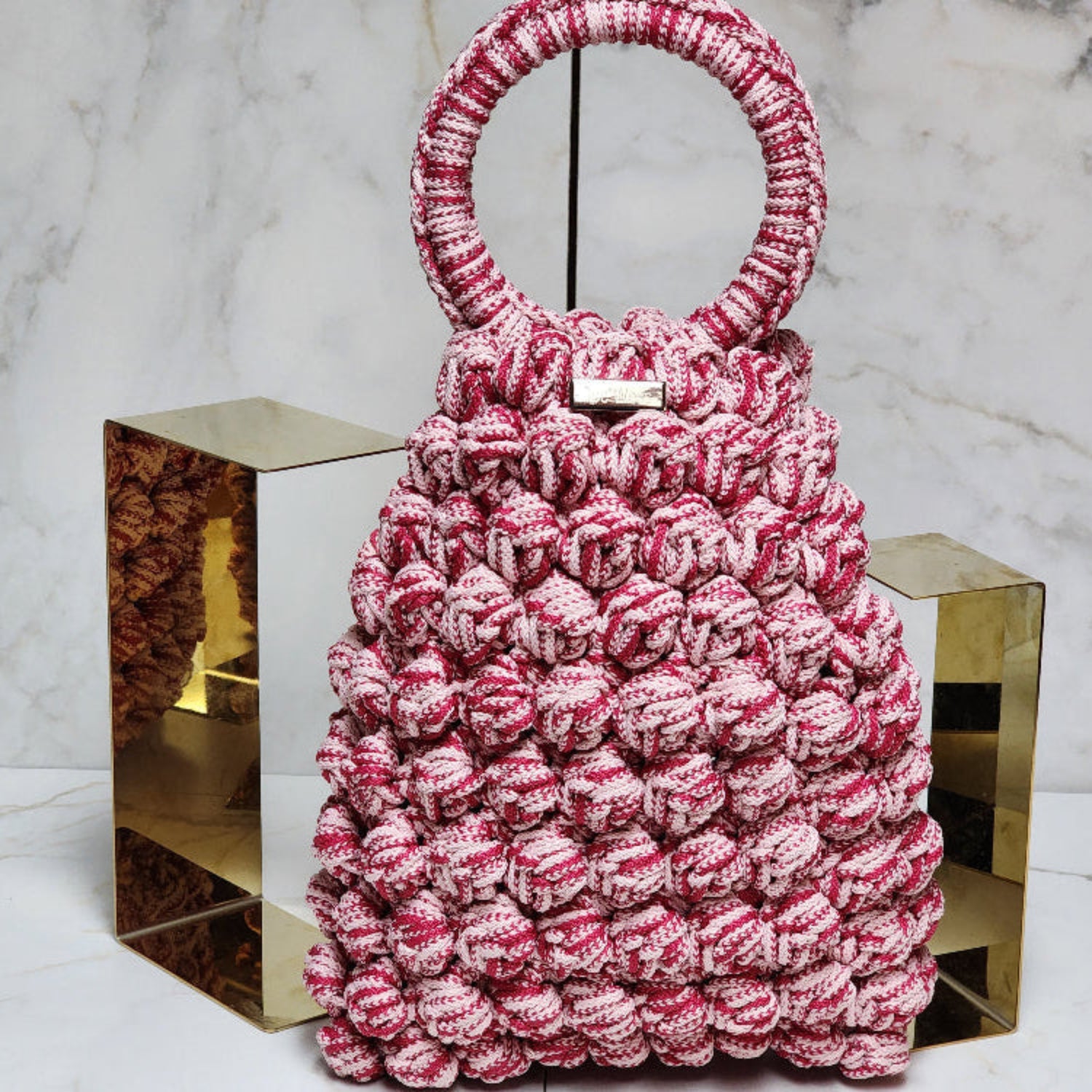 Handcrafted pink crochet purse with delicate stitching and a chic, modern shape.