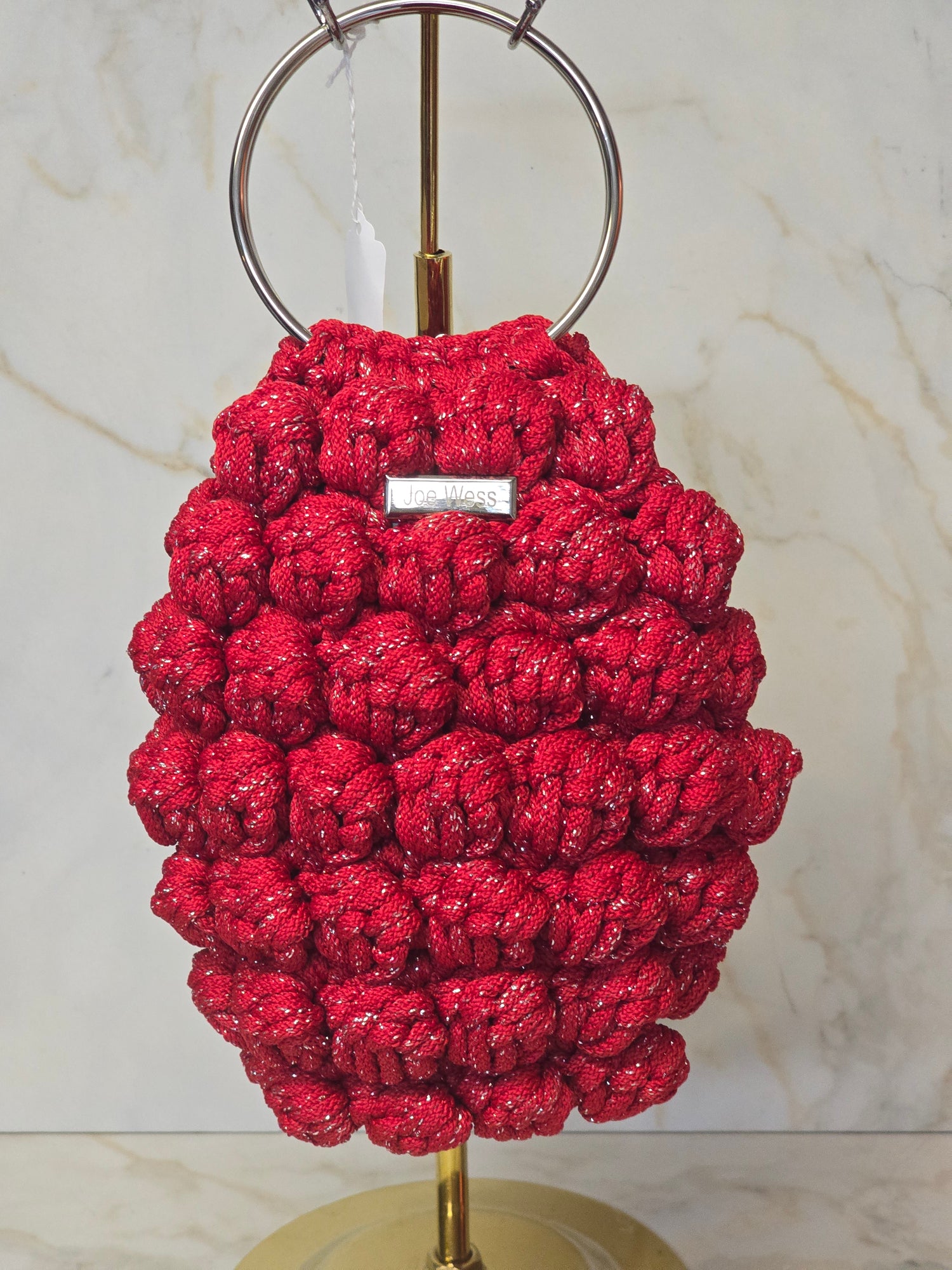 Handcrafted red crochet purse with textured stitching and a sleek, stylish shape.